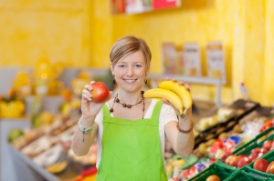 Friendly saleswoman showing different fruits